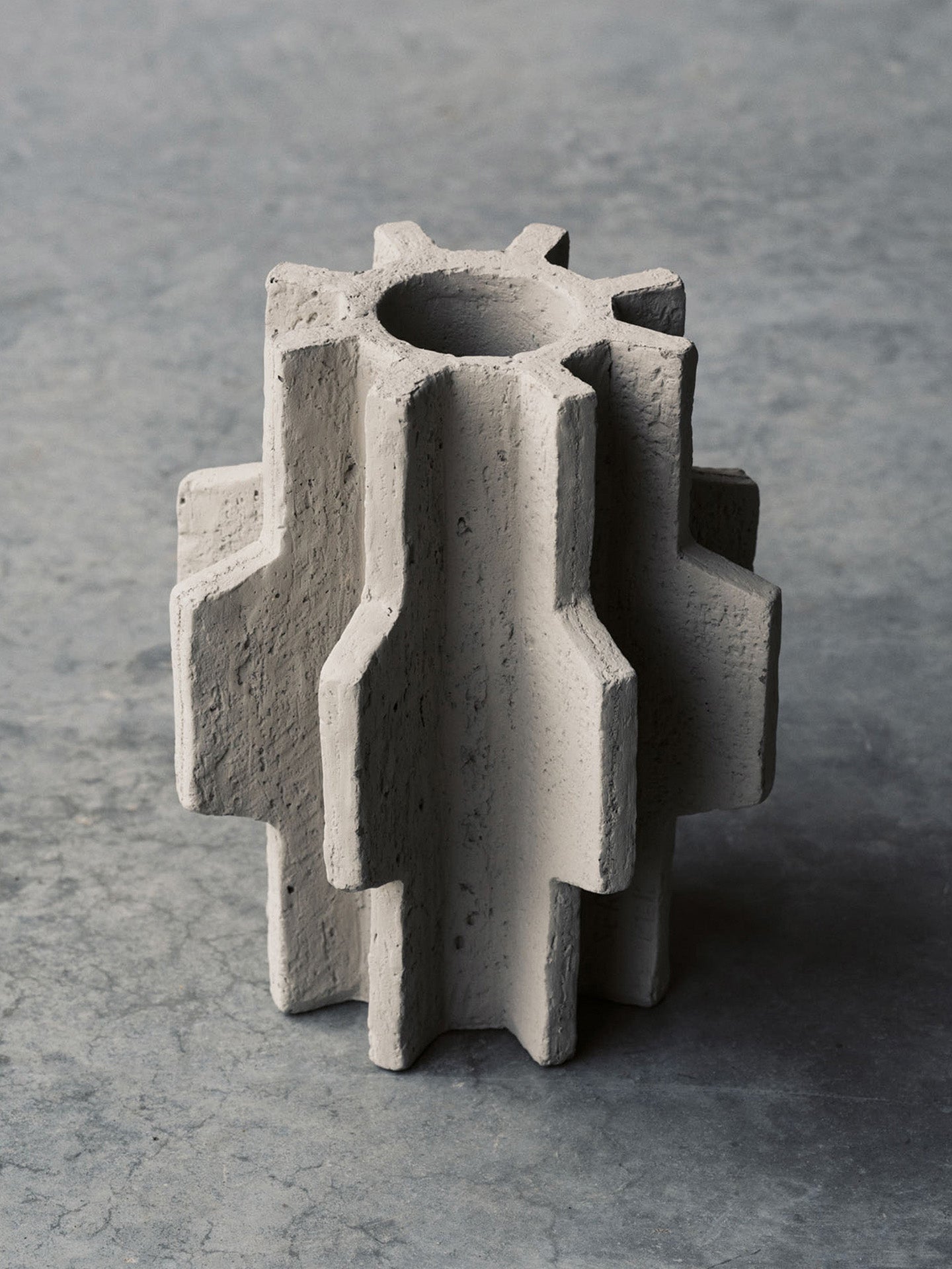 Concrete gear-like sculpture on a gray background