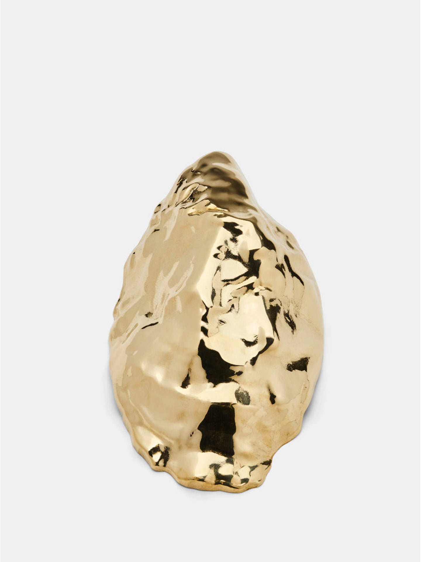 Gold shell-shaped object on a light gray background