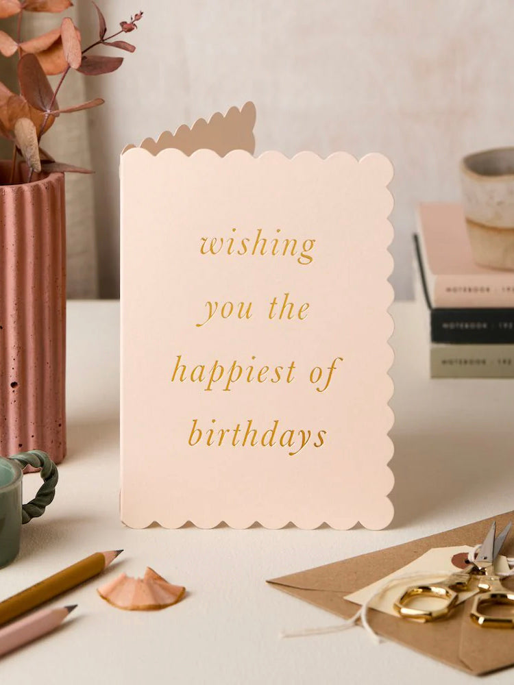 Birthday card with gold text on a desk with stationery items
