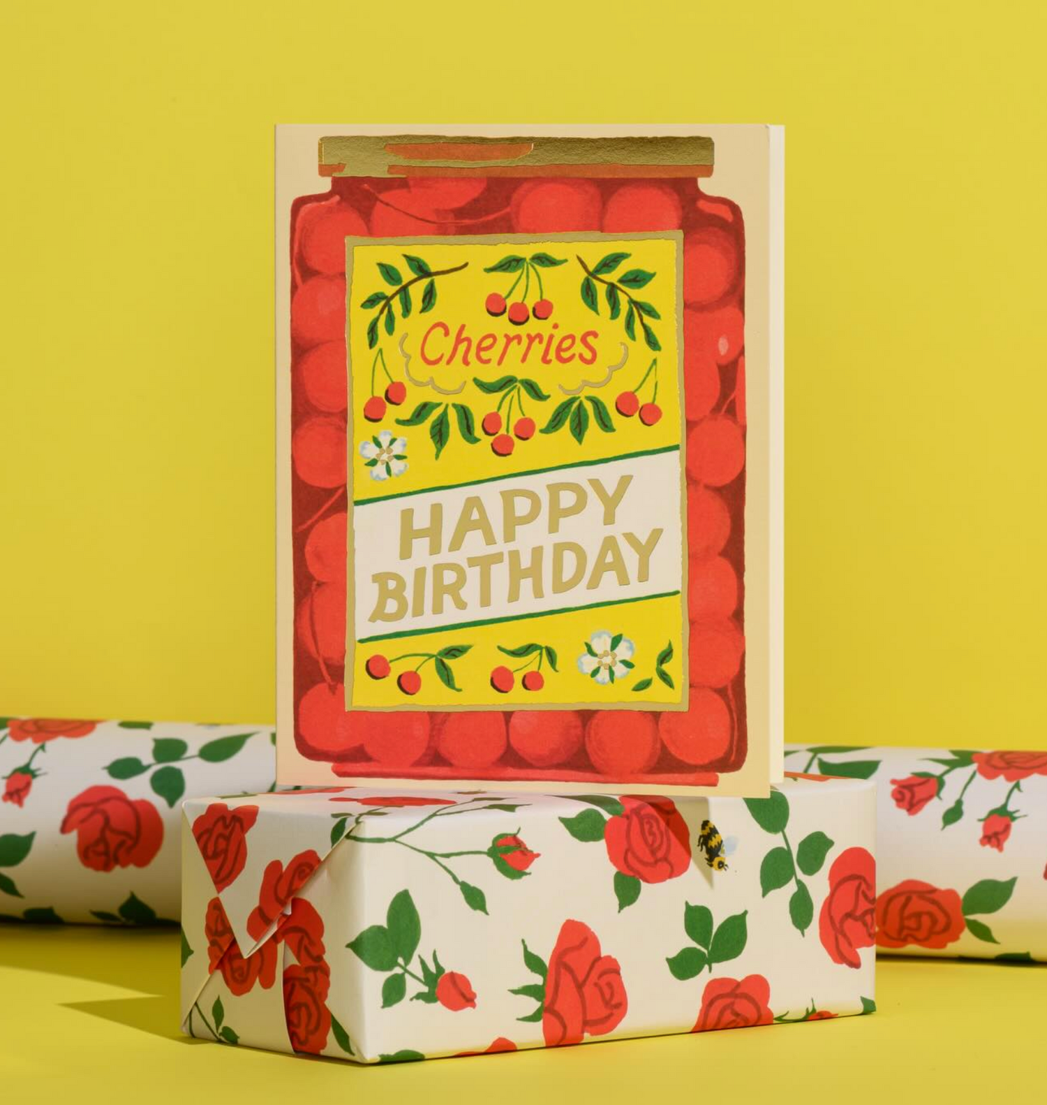Gift wrap with cherry-themed design and 'Happy Birthday' text on a yellow background