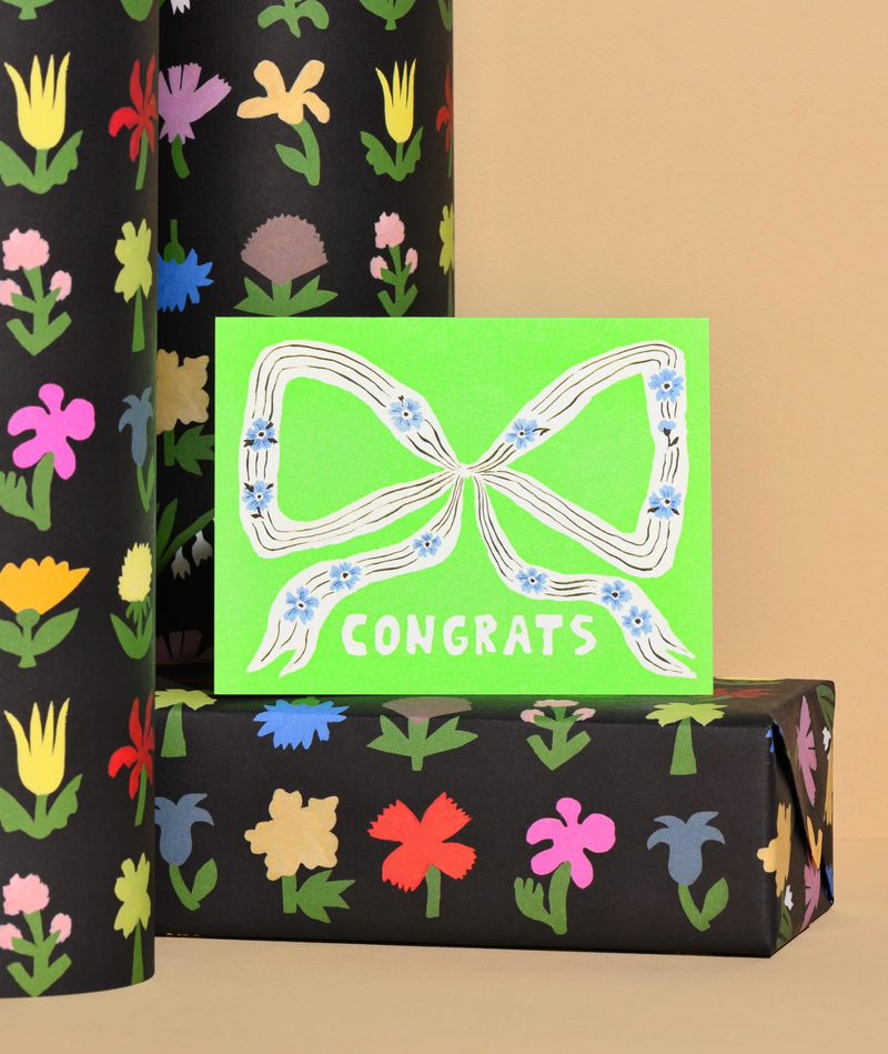 Gift box with floral design and a 'Congrats' card on a beige background