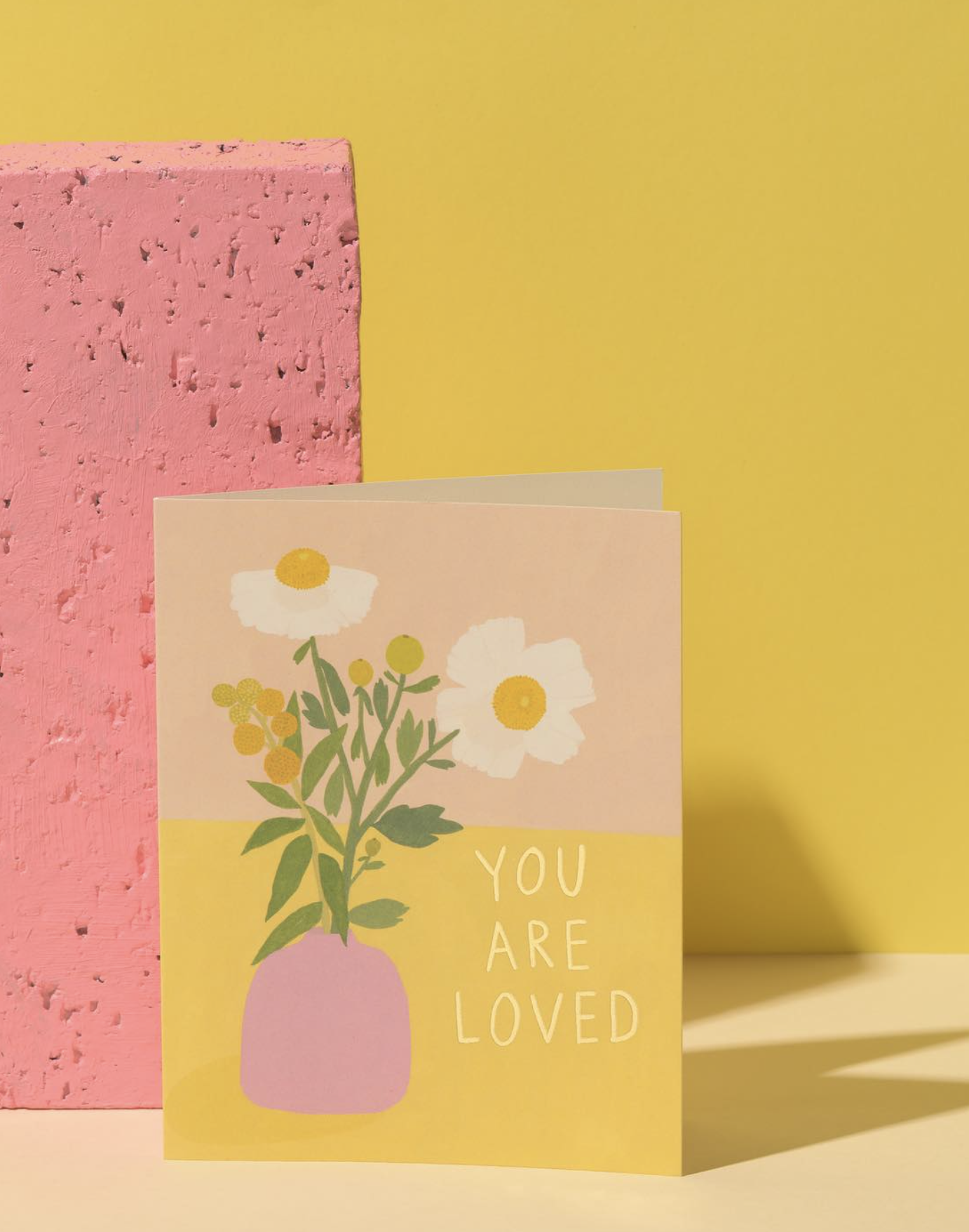 Greeting card with floral design and 'You are loved' text on a yellow background