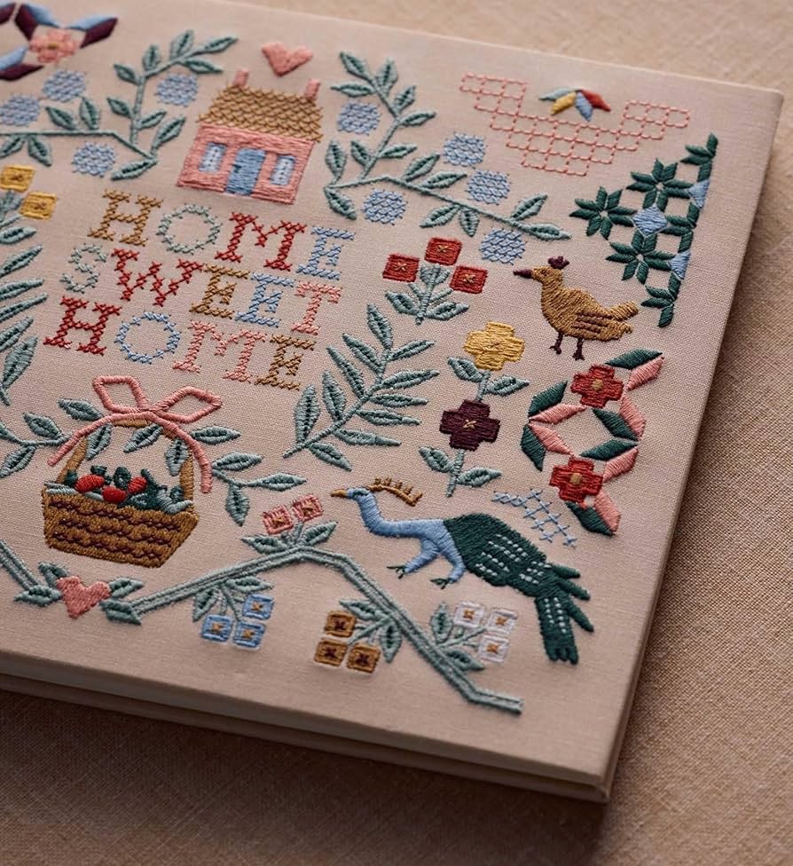 Guest book featuring embroidery with 'Home Sweet Home' text and various decorative elements on a beige background