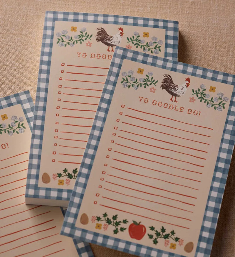 Set of stationery items with checkered border and decorative elements on a wooden surface.