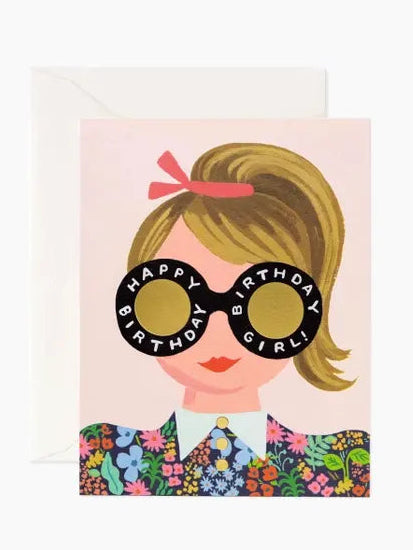 A birthday card featuring an illustration of a girl with sunglasses that say 'Happy Birthday Girl'. She has a red bow in her hair and is wearing a floral dress.