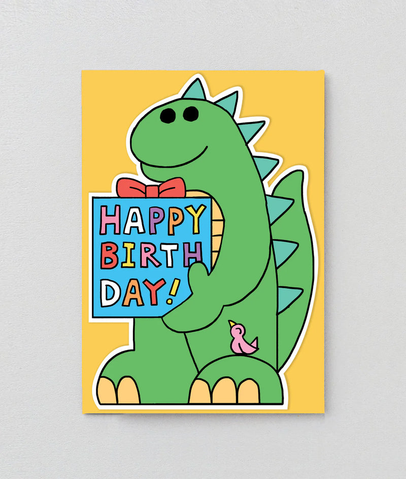 Birthday card with a green dinosaur holding a 'Happy Birthday!' sign on a yellow background
