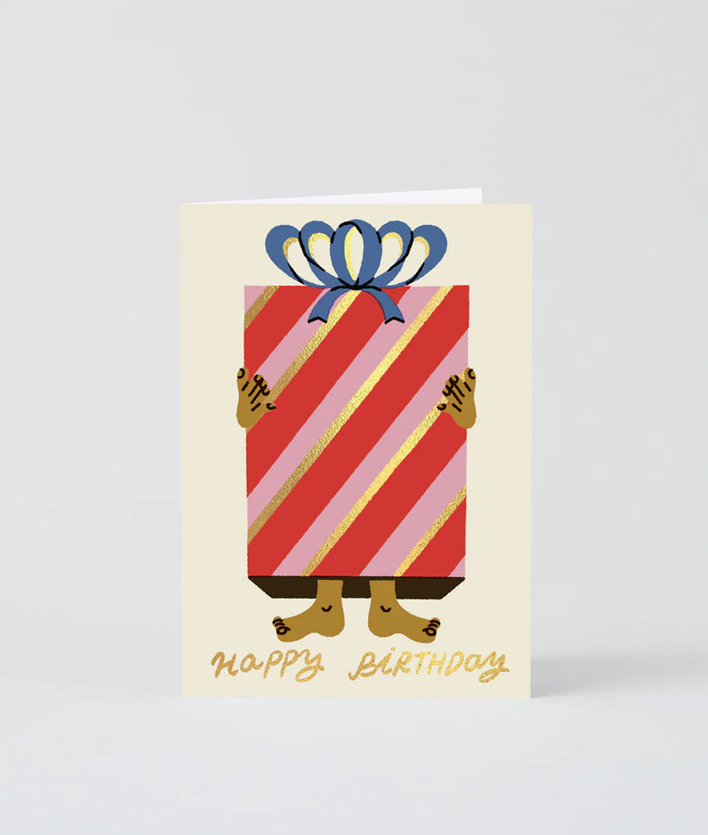 Birthday card with a striped gift box and feet holding it, on a light gray background