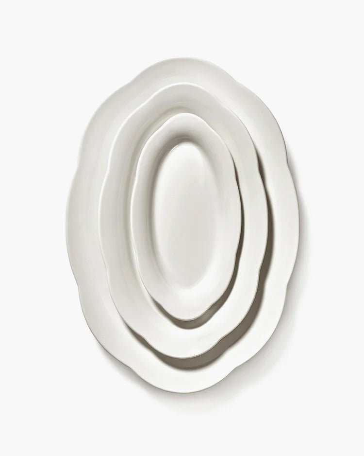 Set of three white ceramic plates of different sizes on a white background