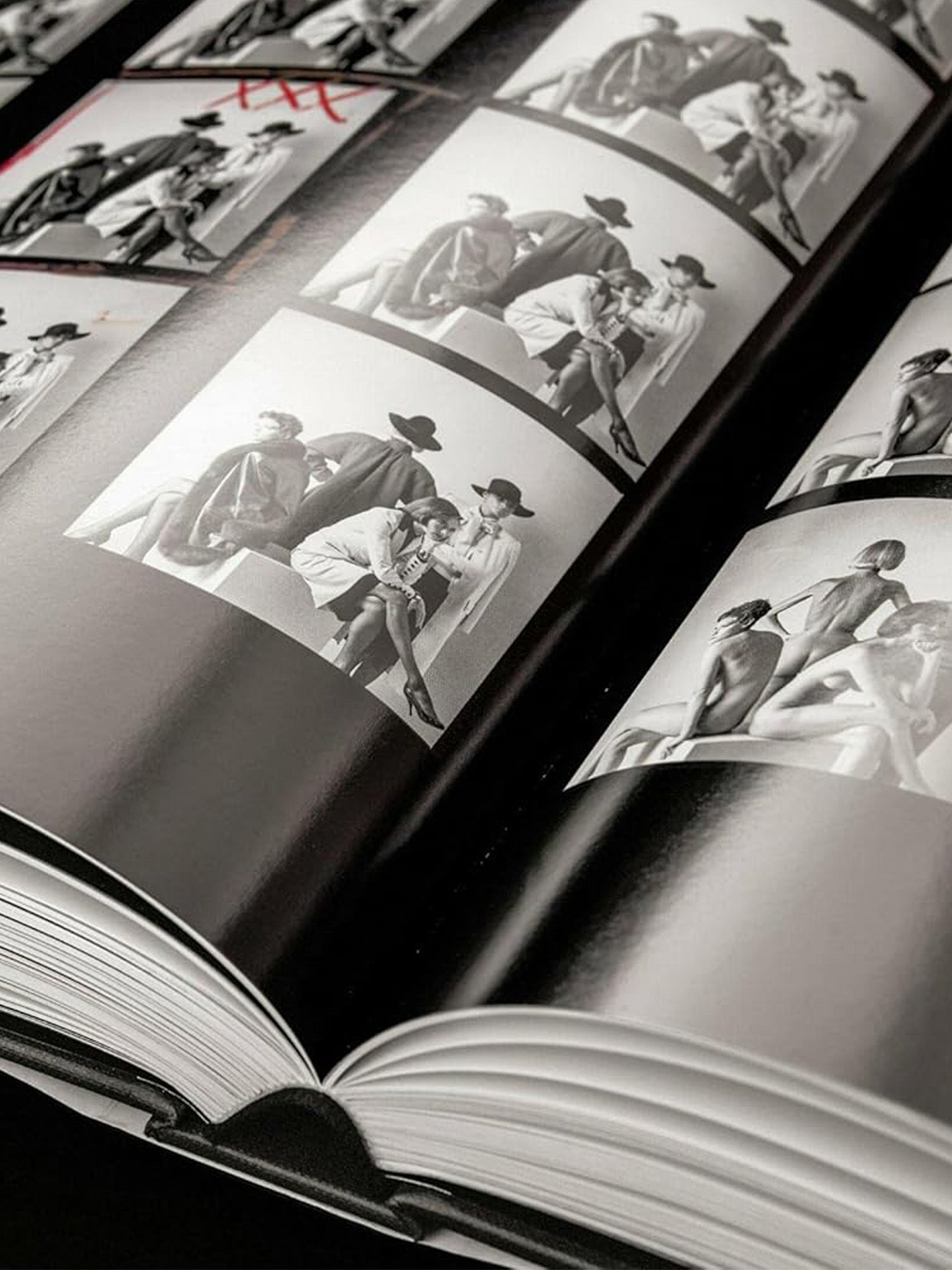 Open book with Helmut Newton's black and white contact prints of models in various poses.