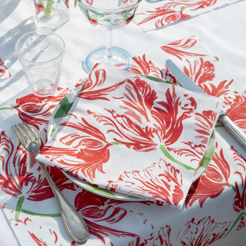 Table setting with floral-patterned tablecloth, napkins, plates, cutlery, and glasses.