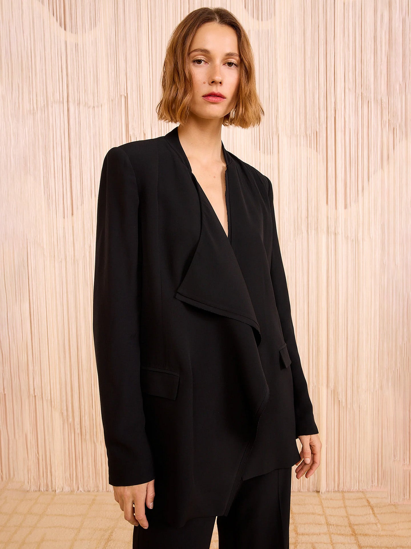 Woman wearing a black blazer against a wooden paneled wall