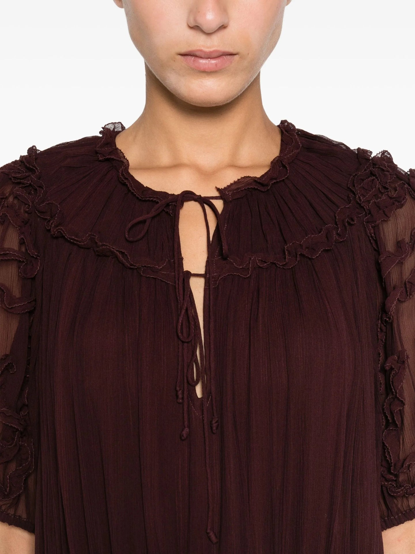Close-up of a  burgundy dress with ruffled details on a plain background