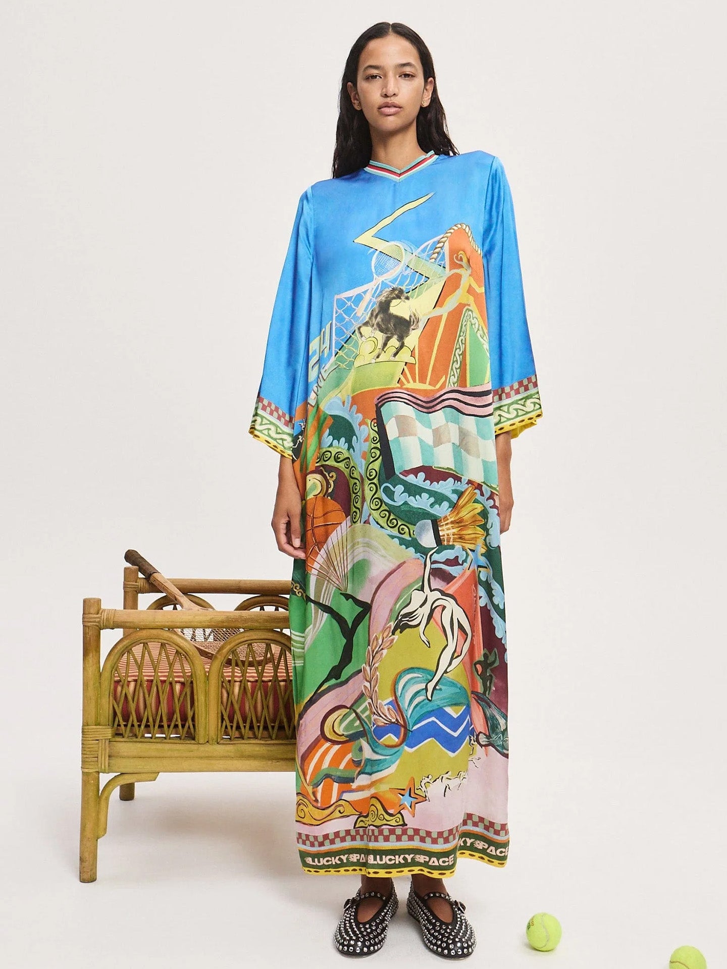 Woman wearing Alemais' colorful silk dress with abstract patterns on a white background