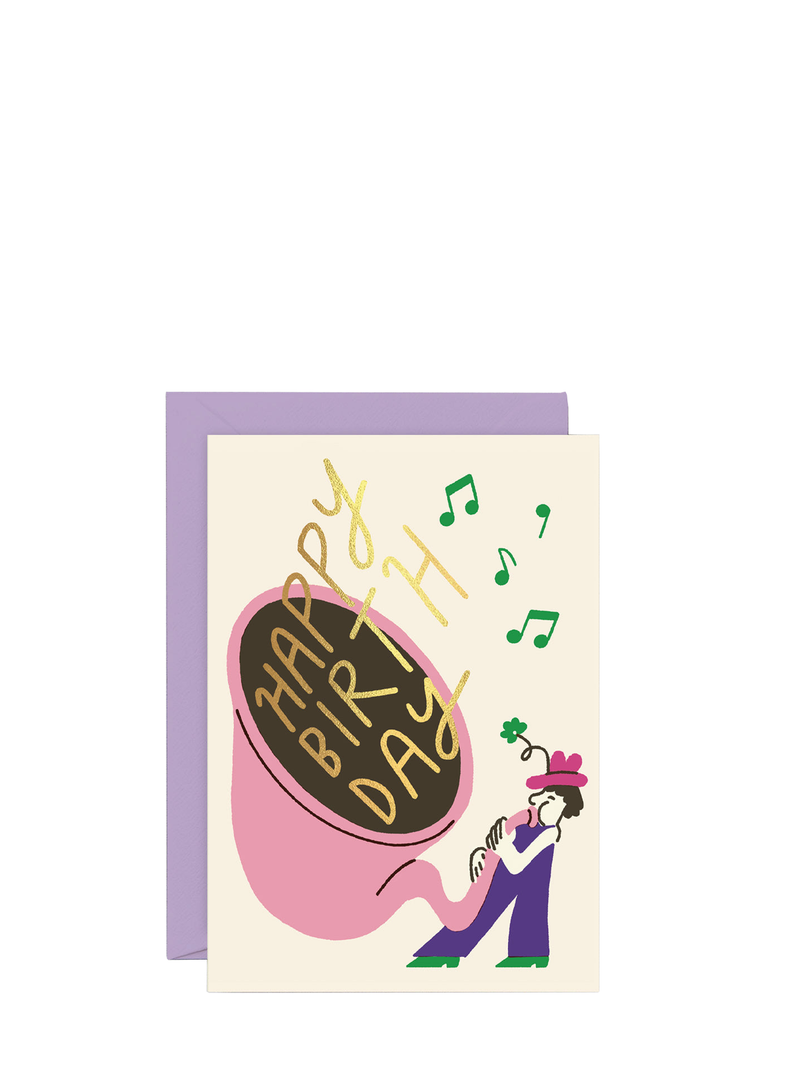 A birthday card featuring a musical theme with a large Tuba at the center, surrounded by musical notes, and a small figure of a person wearing a hat. The card is colorful with gold foil detailing.