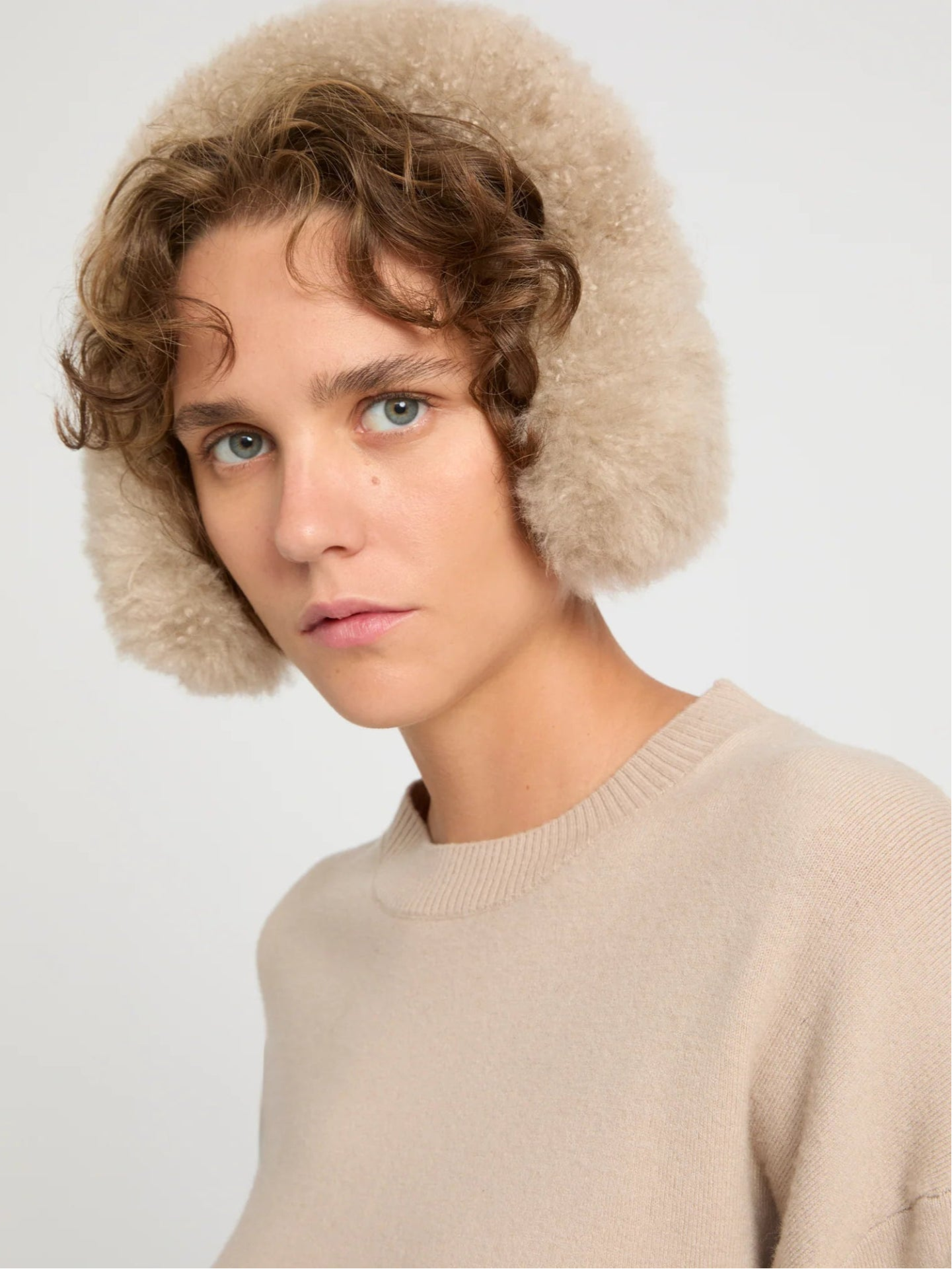 Person wearing a beige earmuffs against a white background