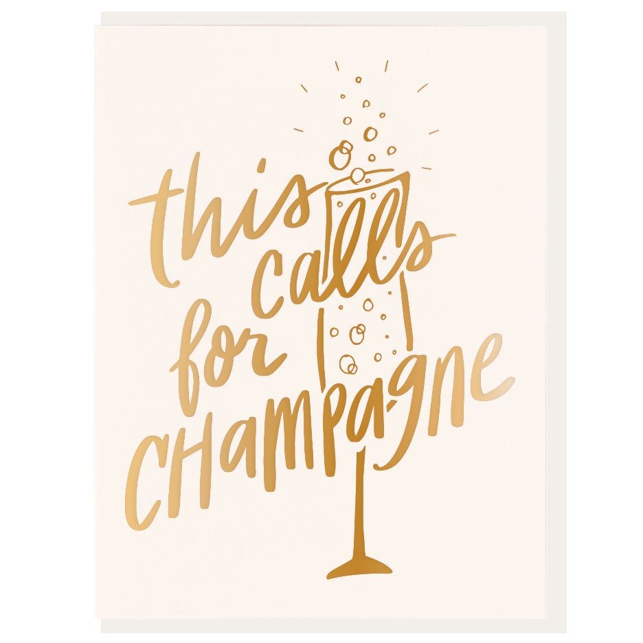 A folded greeting card with the text 'This Calls for Champagne' printed in gold foil on the front, accompanied by an illustration of a champagne glass with bubbles.